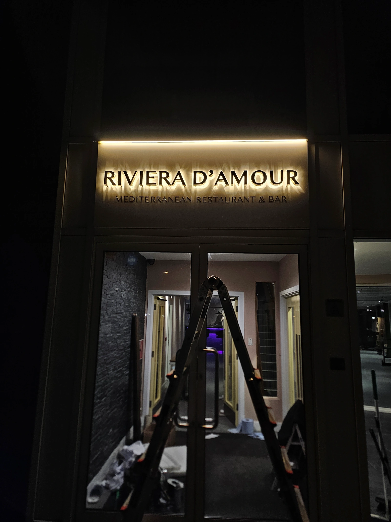 Riviera D'Amour illuminated entrance sign with Mediterranean Restaurant & Bar lettering